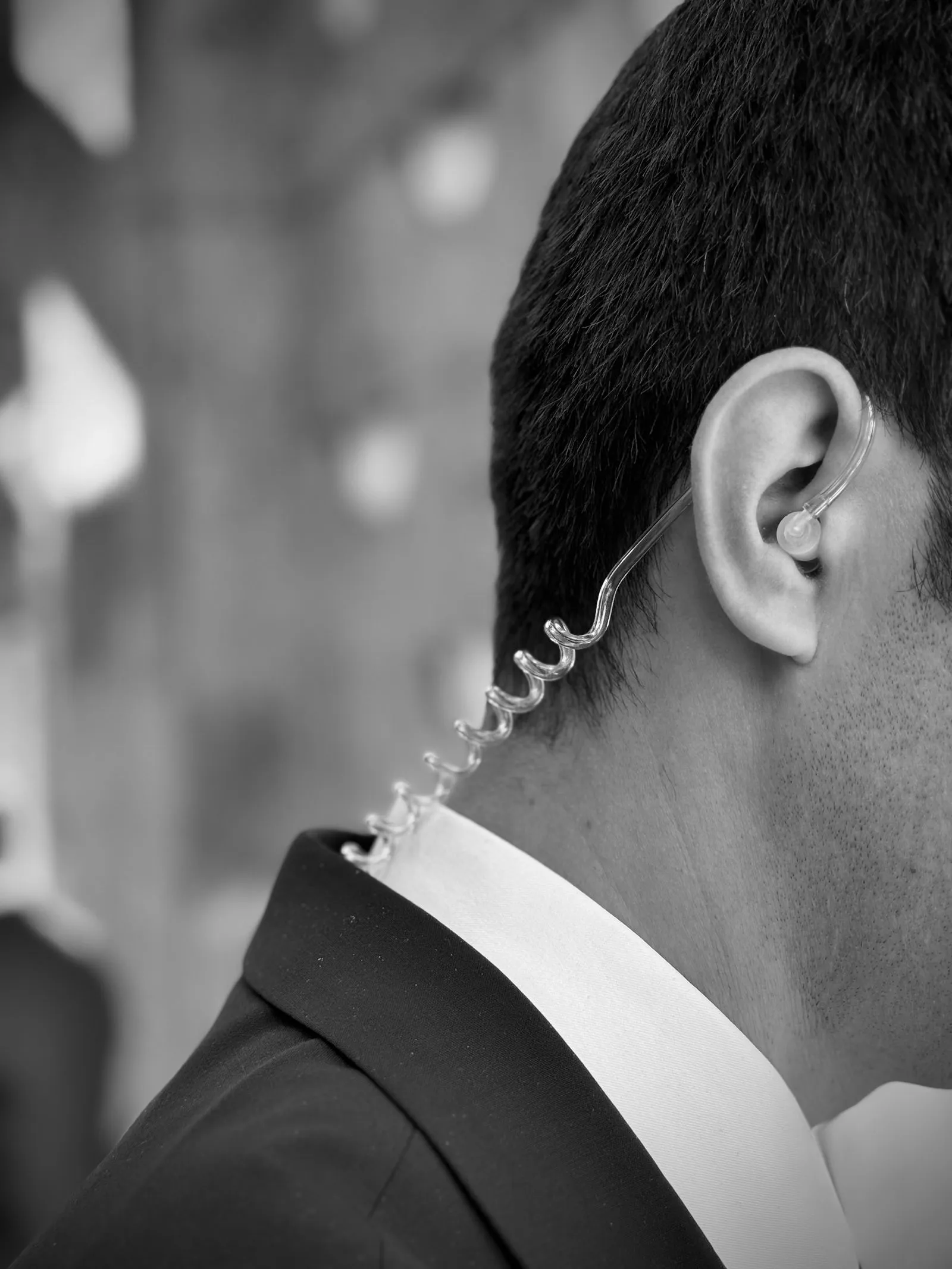 Radio earpiece worn by a close-protection officer in a dark suit