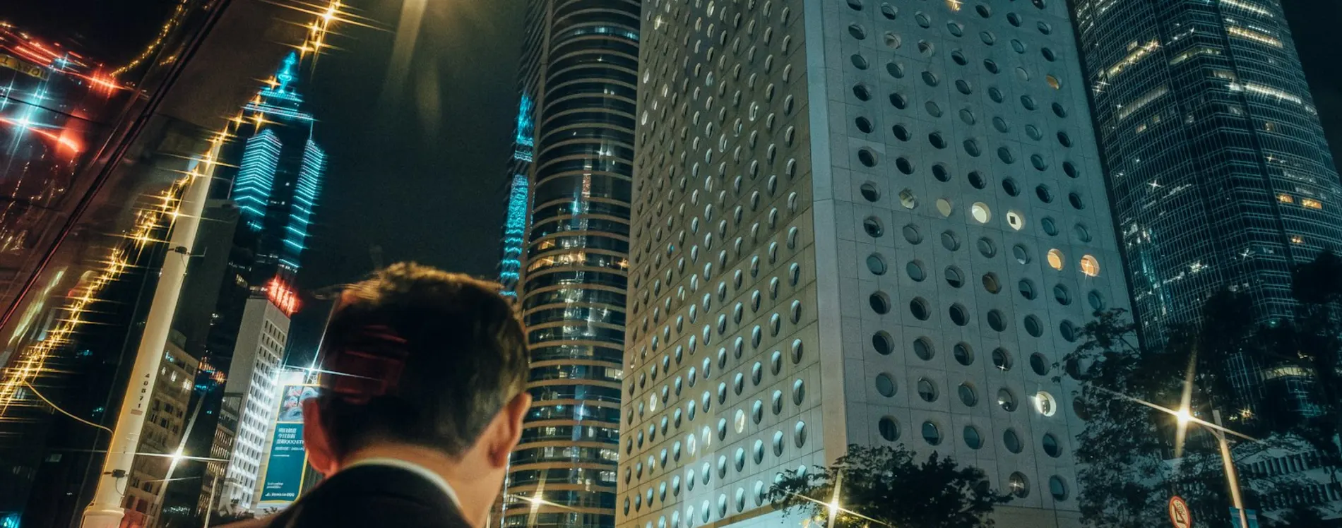Principal in a dark suit being moved to a vehicle at night